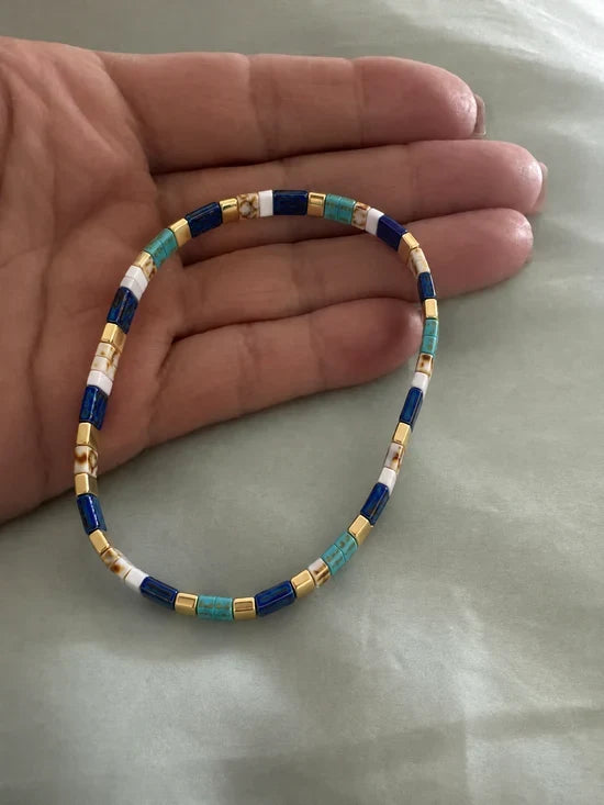 Customer photo: a Miyuki glass tile bracelet in blue, turquoise, white and gold held in a hand
